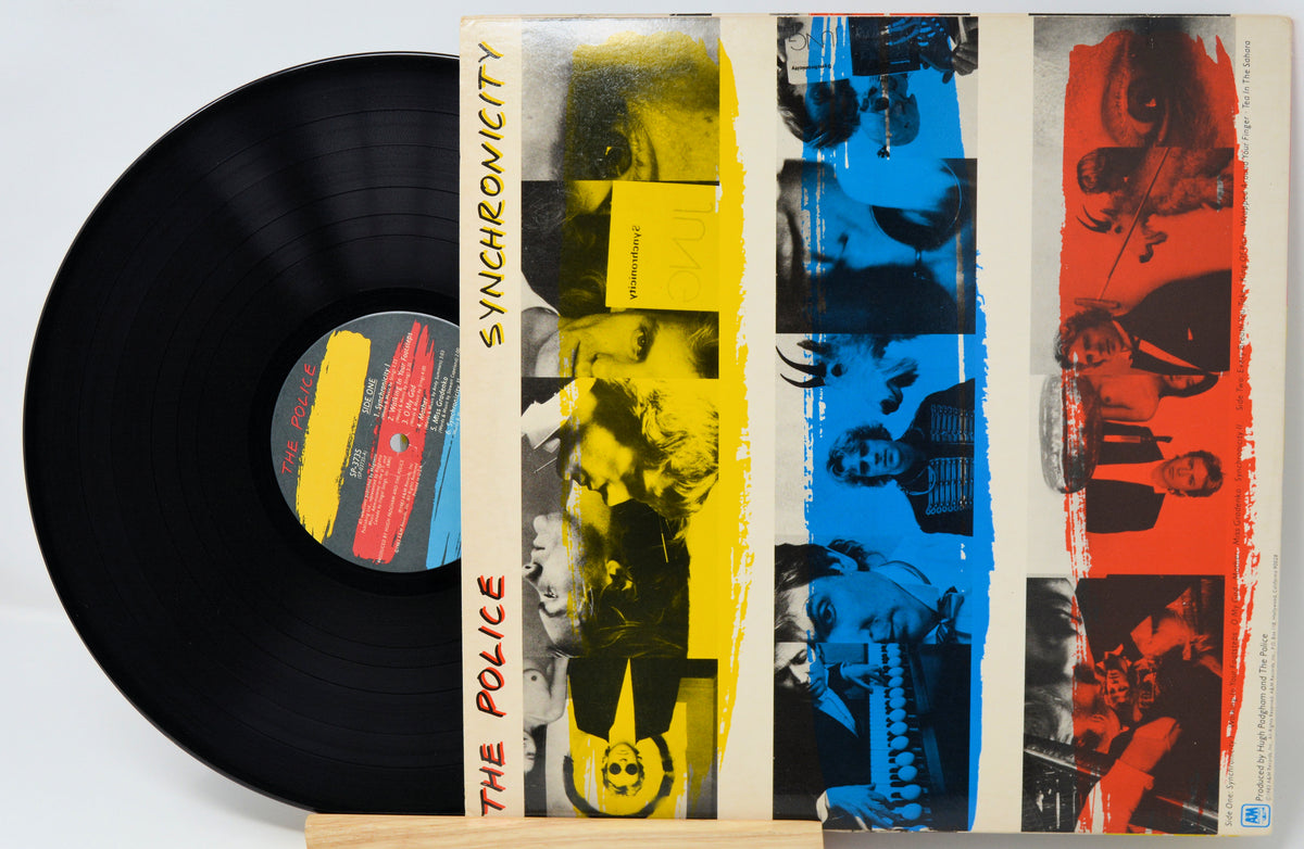 The Police 'Synchronicity' vinyl record LP with its illustrated cover sleeve, displayed on a light wood stand against a white background.