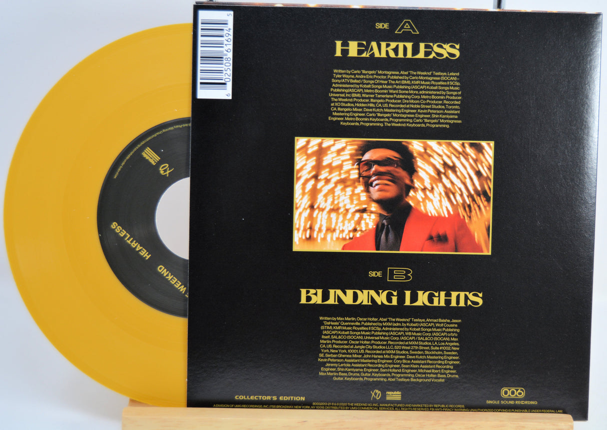 The Weekend Heartless variant #8 7 Inch Vinyl record with a black front cover featuring a person wearing sunglasses and a red jacket, and a yellow record inside.