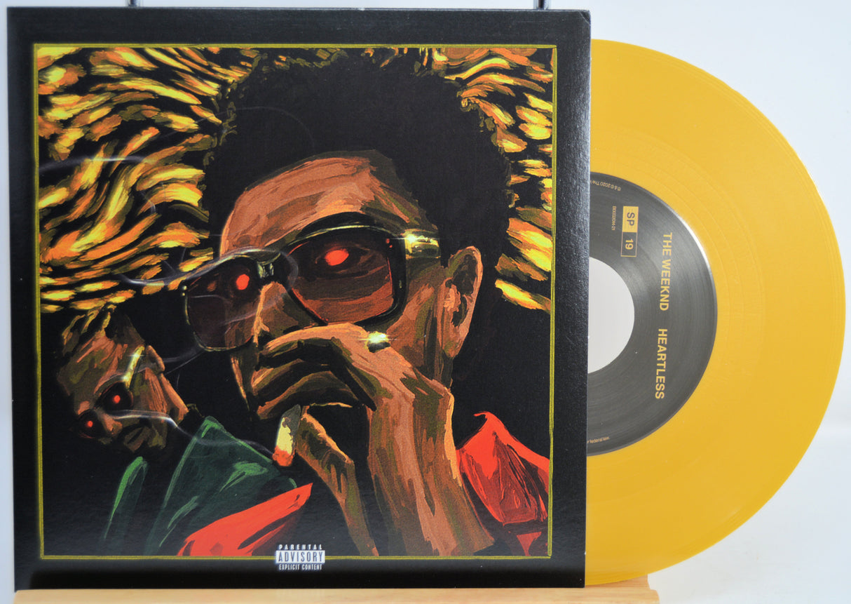 The Weekend Heartless variant #9 7 Inch Vinyl record with a black front cover featuring a person wearing sunglasses and a red jacket, and a yellow record inside.