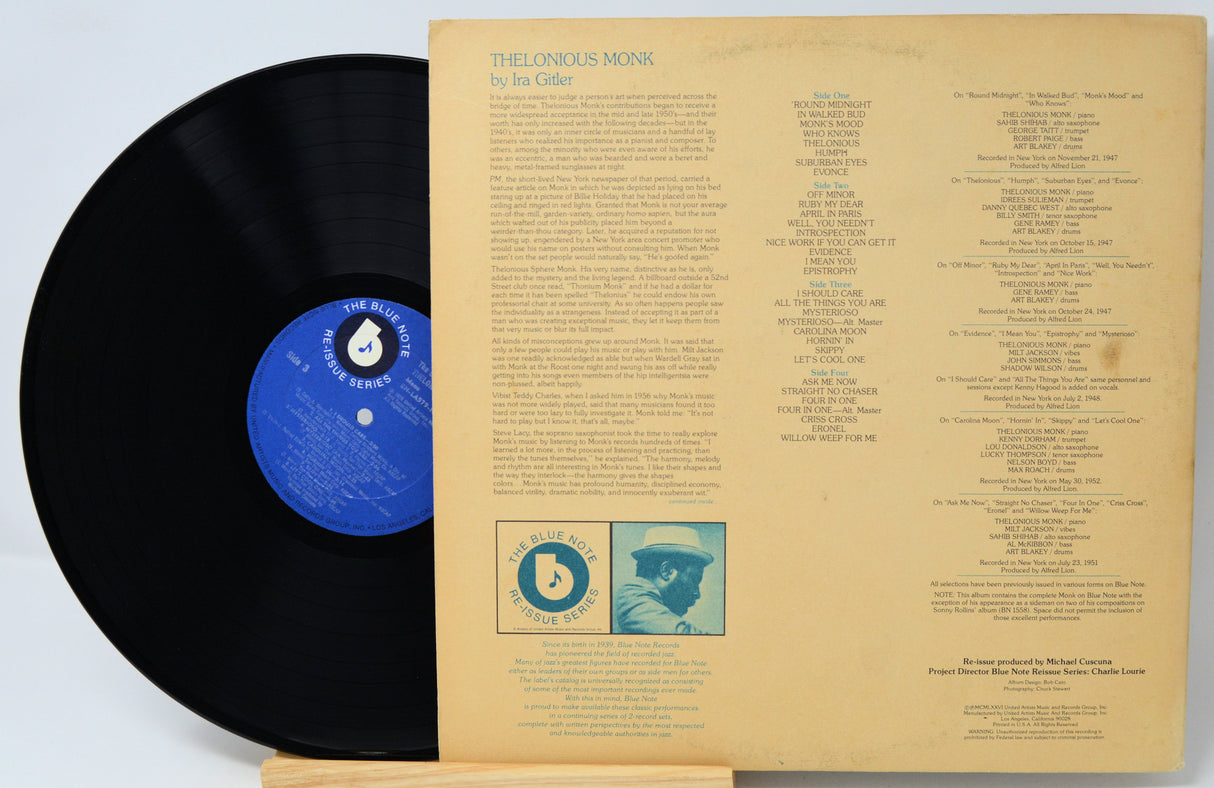 A vinyl record partially pulled from its sleeve, showing the black record with a blue label next to the back cover of the album 'The Loudous Monk' by Joe Cade. The sleeve is a warm beige color with printed track listings and a small illustrated portrait.