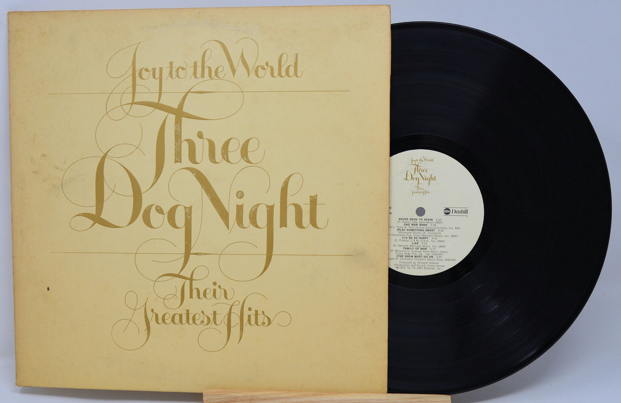 Vinyl record with gold cover featuring 'Three Dog Night' text on a light blue background