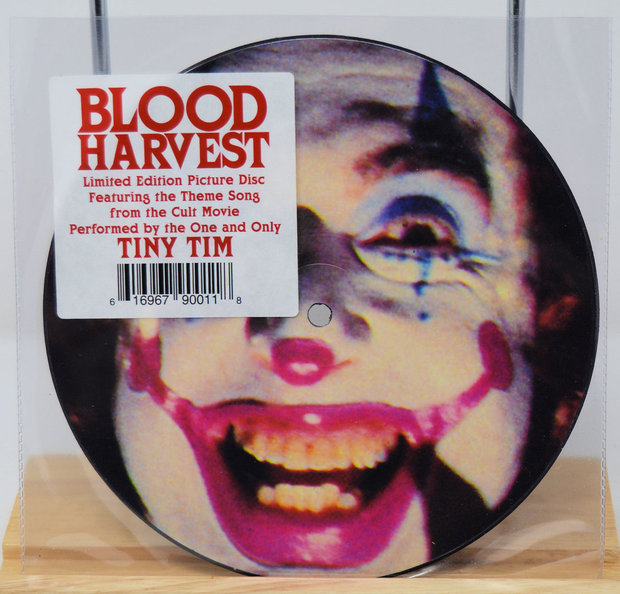 Vinyl record with a face design and 'Blood Harvest' label on a wooden surface.