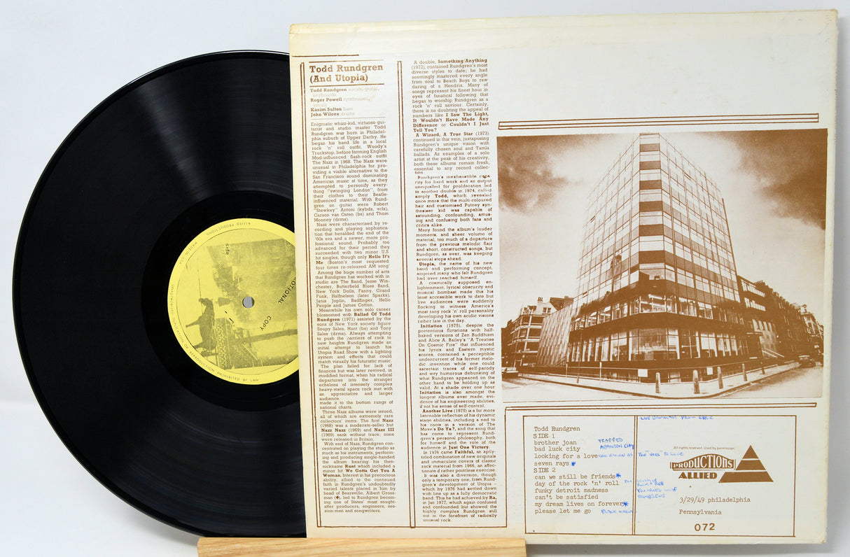 Vinyl record with a yellow label and its cover showing text and an illustration of a building.