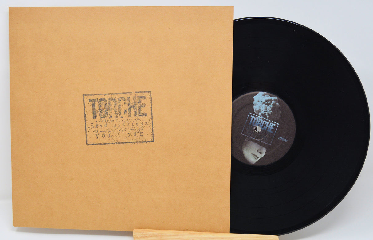 Vinyl record with a brown sleeve featuring a logo on a light gray background