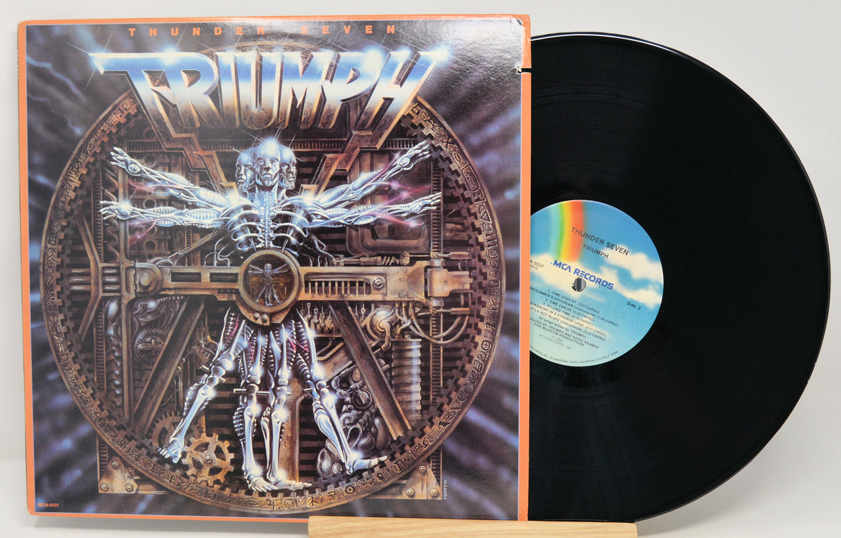 Triumph 'Thunderstagen' vinyl record LP with the illustrated album cover standing beside the black record on a small wooden stand.