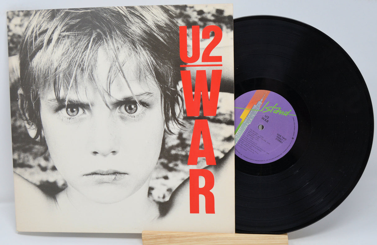 A used vinyl record of U2 album 'War' with the cover displaying a black and white photo of a child. The album title 'U2 - WAR' is prominently shown in red text on the upper part of the cover.
