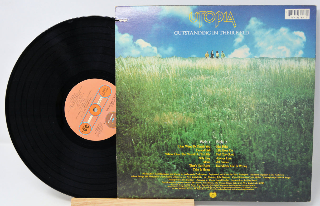 Vinyl record with a 'Utopia' album cover featuring a grassy field and sky.