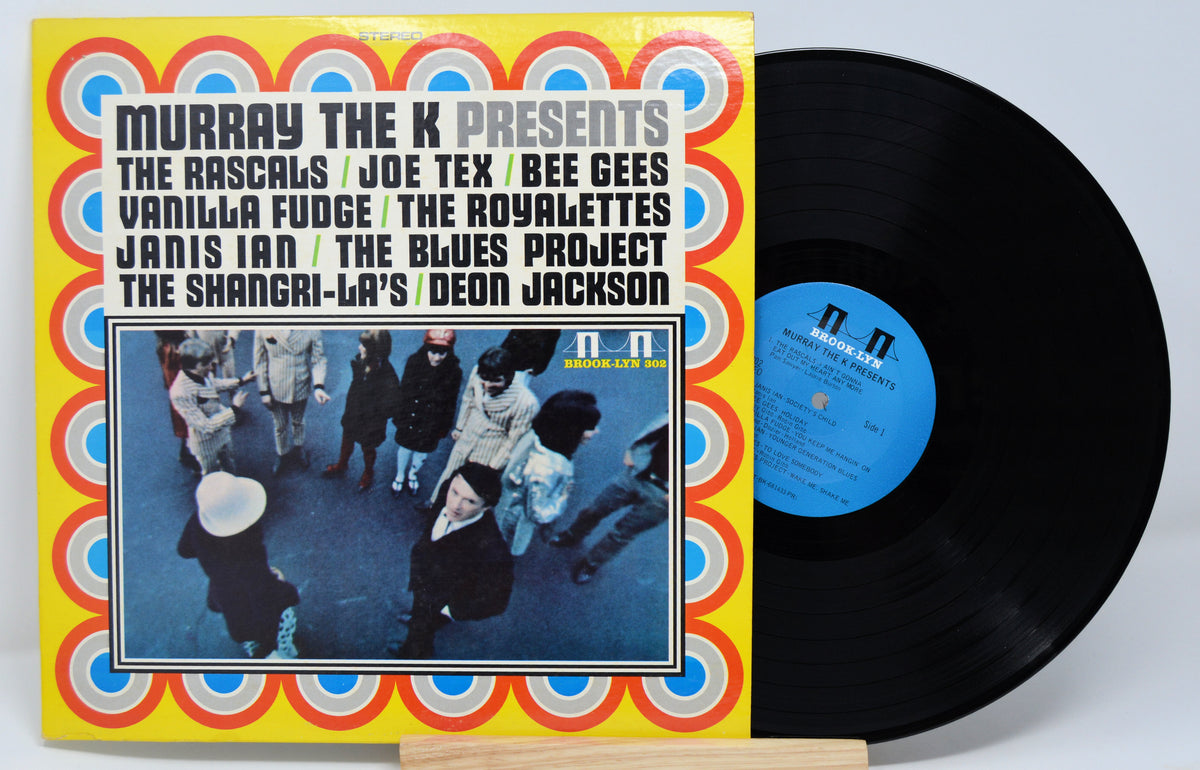 Vinyl record with colorful cover featuring artist names and a band photo.
