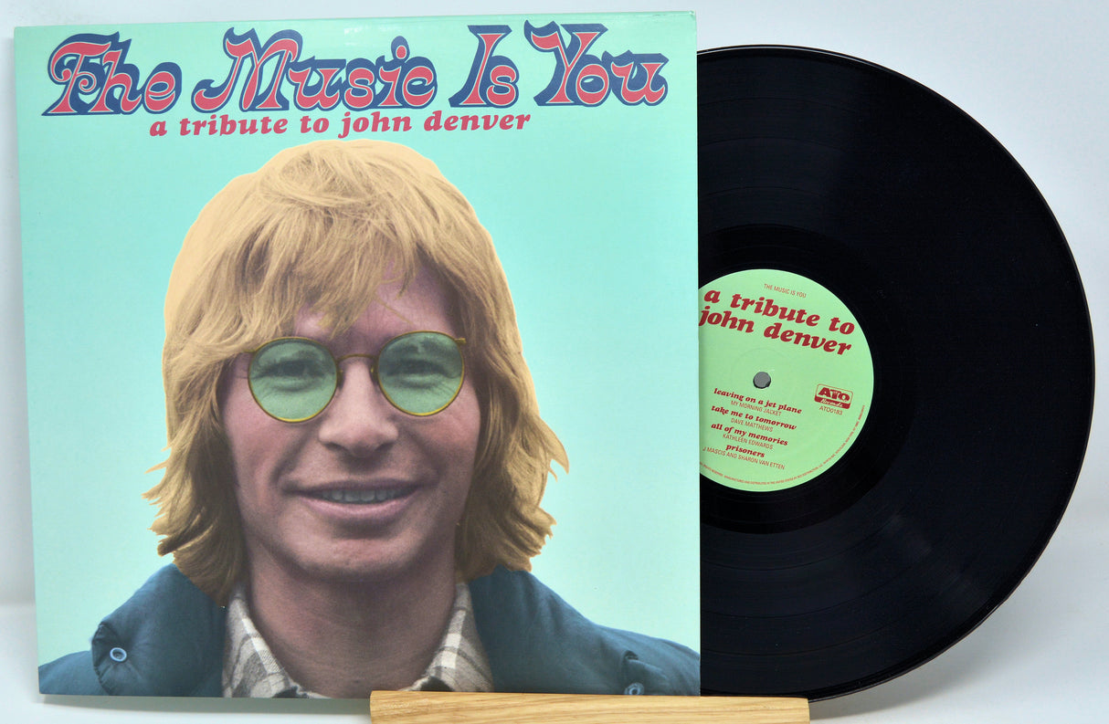 Vinyl record with cover featuring a tribute to John Denver on a light blue background