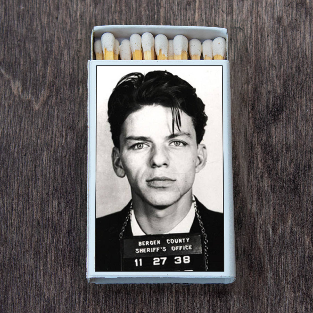 Retro matchbox featuring a vintage black and white mugshot photo on wood background