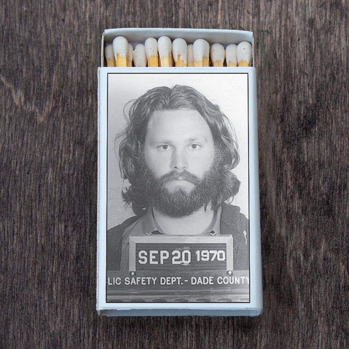 Retro matchbox with a black-and-white vintage mugshot on top, displayed on a wooden surface