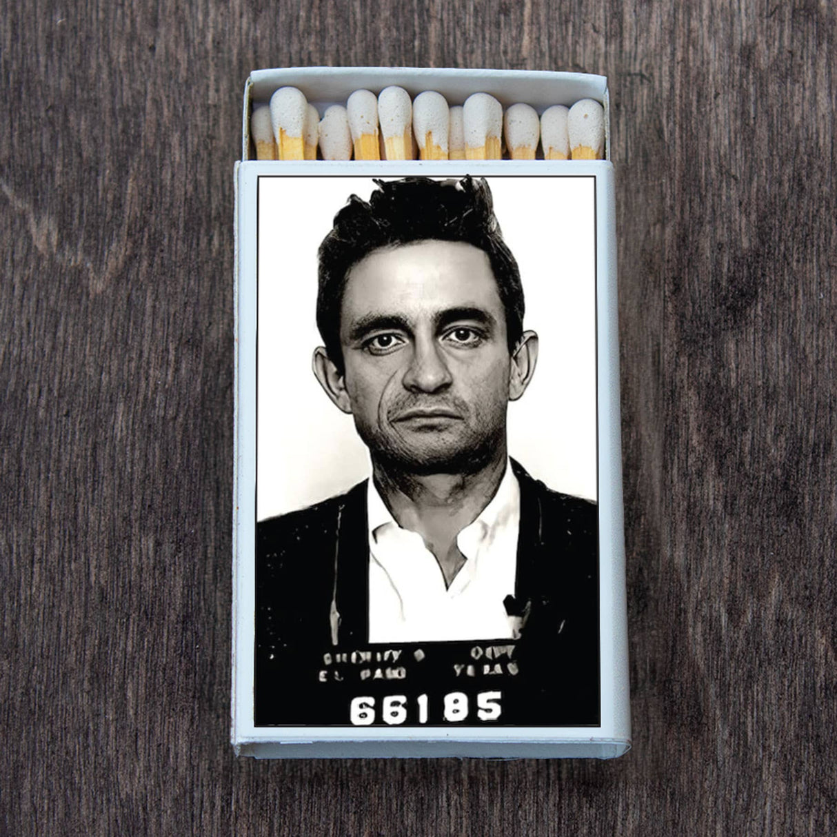Decorative matchbox featuring a vintage mugshot portrait on the cover against a wooden background