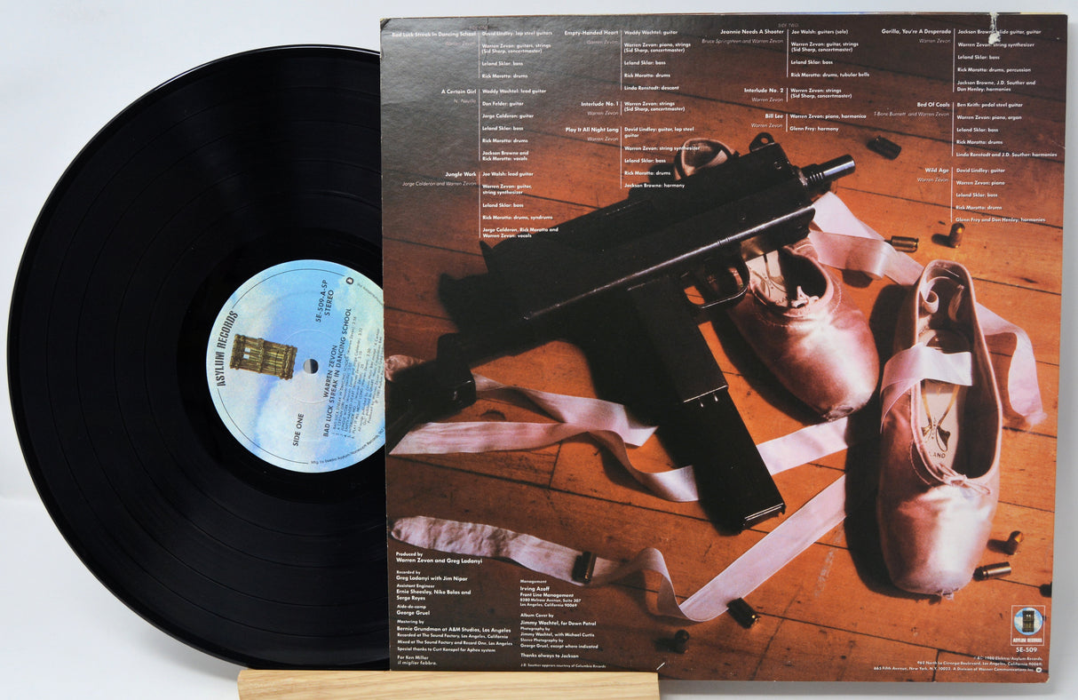 Vinyl record with a cover featuring a gun and shoes on a wooden floor.