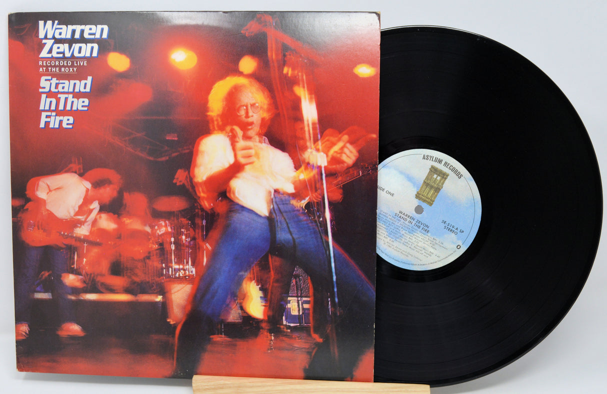 Vinyl record with cover featuring a musician and album title 'Stand In The Fire' by Warren Zevon.