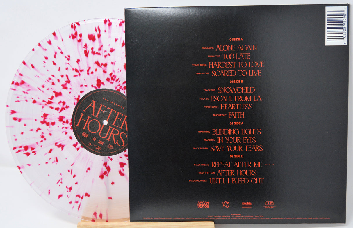 Vinyl record with pink splatter design and black cover displaying tracklist.