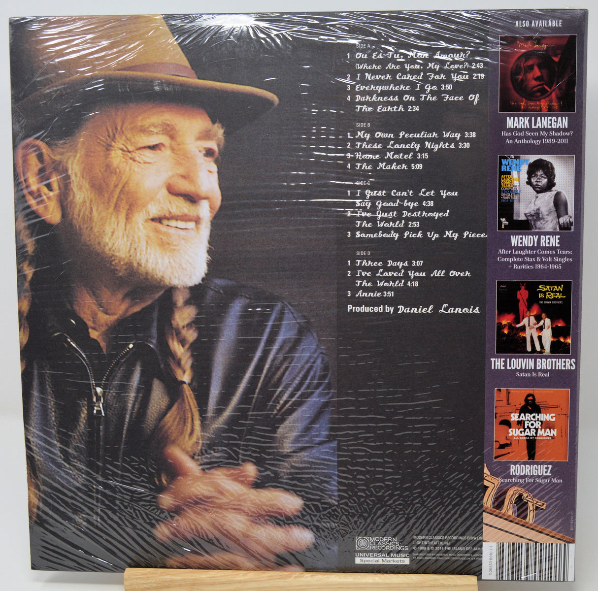 Back cover of a CD album for Randy Sandlin, wrapped in protective plastic and displayed on a small wooden stand. The cover features a large portrait of Randy Sandlin on the left, a tracklist in the center, and several artist and collaborator portrait inserts along the right side.
