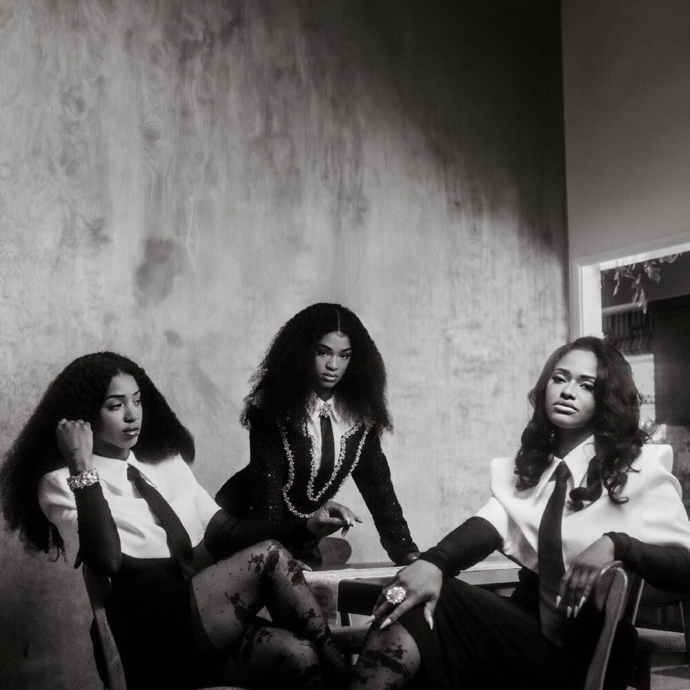 Black and white photo of three women sitting together in a room with a textured wall.
