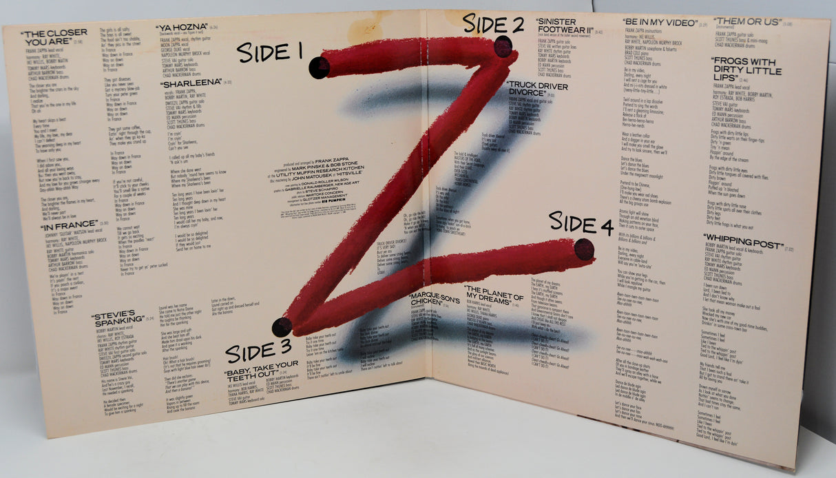 Album cover with a stylized letter 'Z' made of red sticks on a beige background with text.