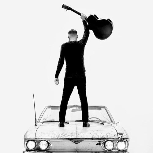 Black and white album cover featuring a person standing on a car with a raised guitar in the air.