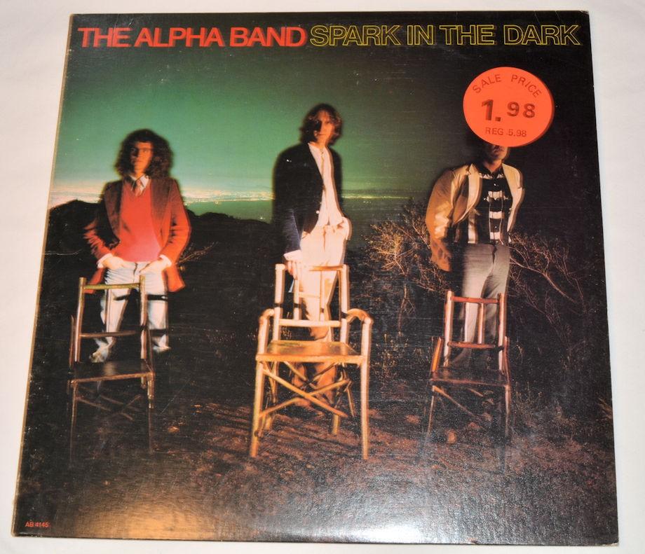 Used vinyl record of The Alpha Band's album 'Spark In the Dark' with a dark background and band members' silhouettes on the cover.