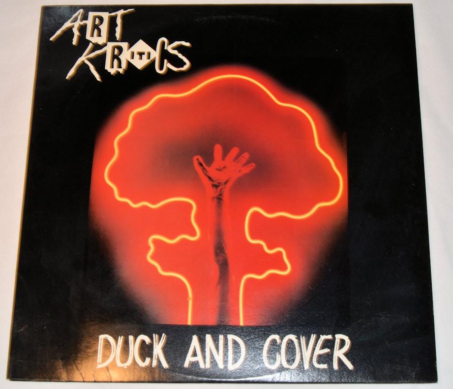 Used vinyl record label for Art Kritics' 'Duck & Cover'. The label features a red background with a silhouette of a duck and a hand, along with the title of the song and the artist's name.
