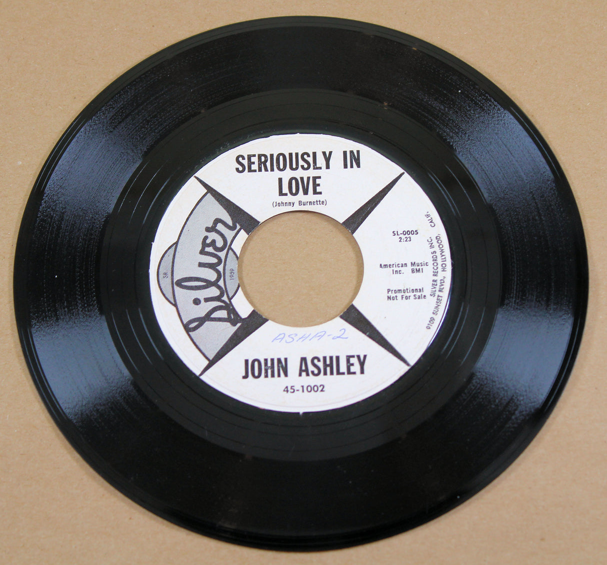A vinyl record labeled 'John Ashley - Seriously In Love' on a plain background.