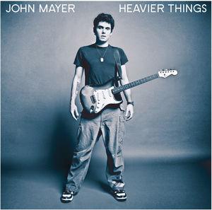 John Mayer with a guitar, wearing a black shirt and jeans, against a blue background, with the album title 'Heavier Things' printed at the top.