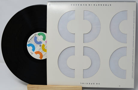 A vinyl record partially pulled from its sleeve, photographed on a light background. The sleeve is off-white with large geometric cutout shapes, and the record label reads Special.