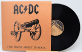 Vinyl record with cover featuring AC/DC logo and cannon illustration on a light gray background