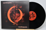 A vinyl record partially pulled from its sleeve, showing the black disc with a red-orange center label and the matching album cover in front.