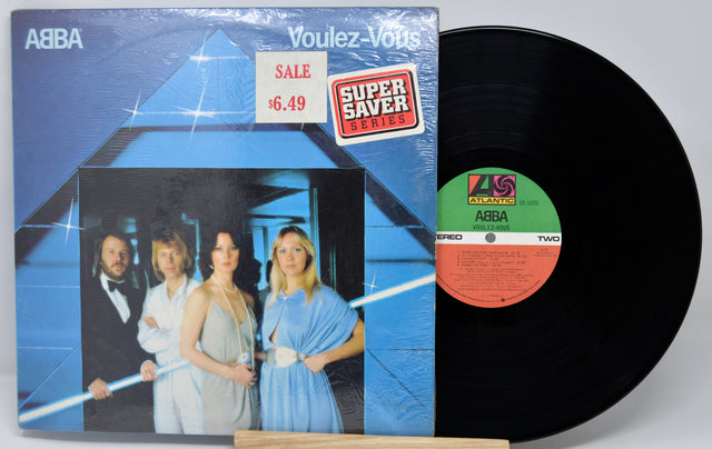 Vinyl record with cover featuring a band and sale tag on a light gray background
