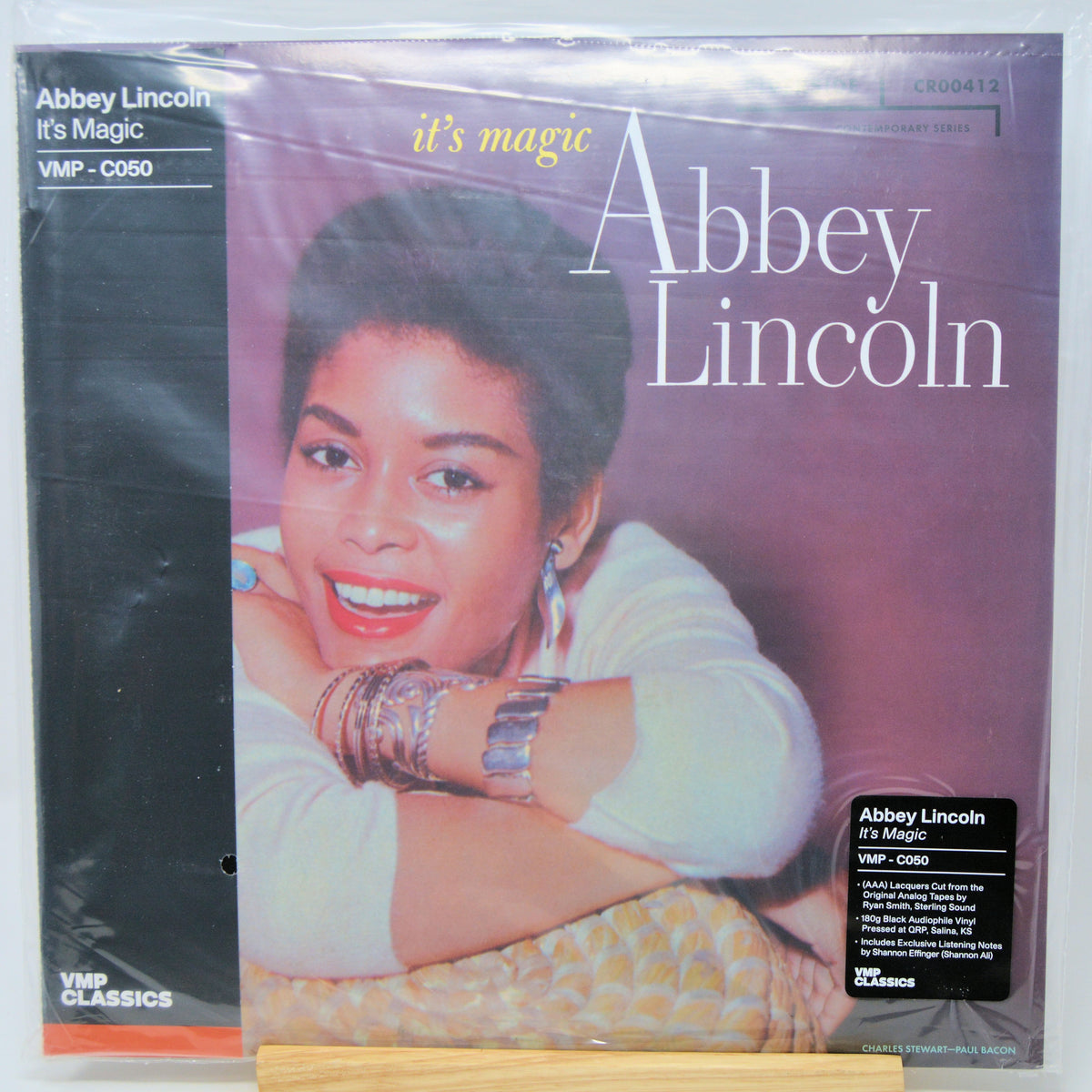 Abbey Lincoln's 'It's Magic' vinyl record LP on a wooden display stand, sealed in its original plastic shrink wrap. The cover art features a portrait of the artist against a purple background, with a black spine band on the left.