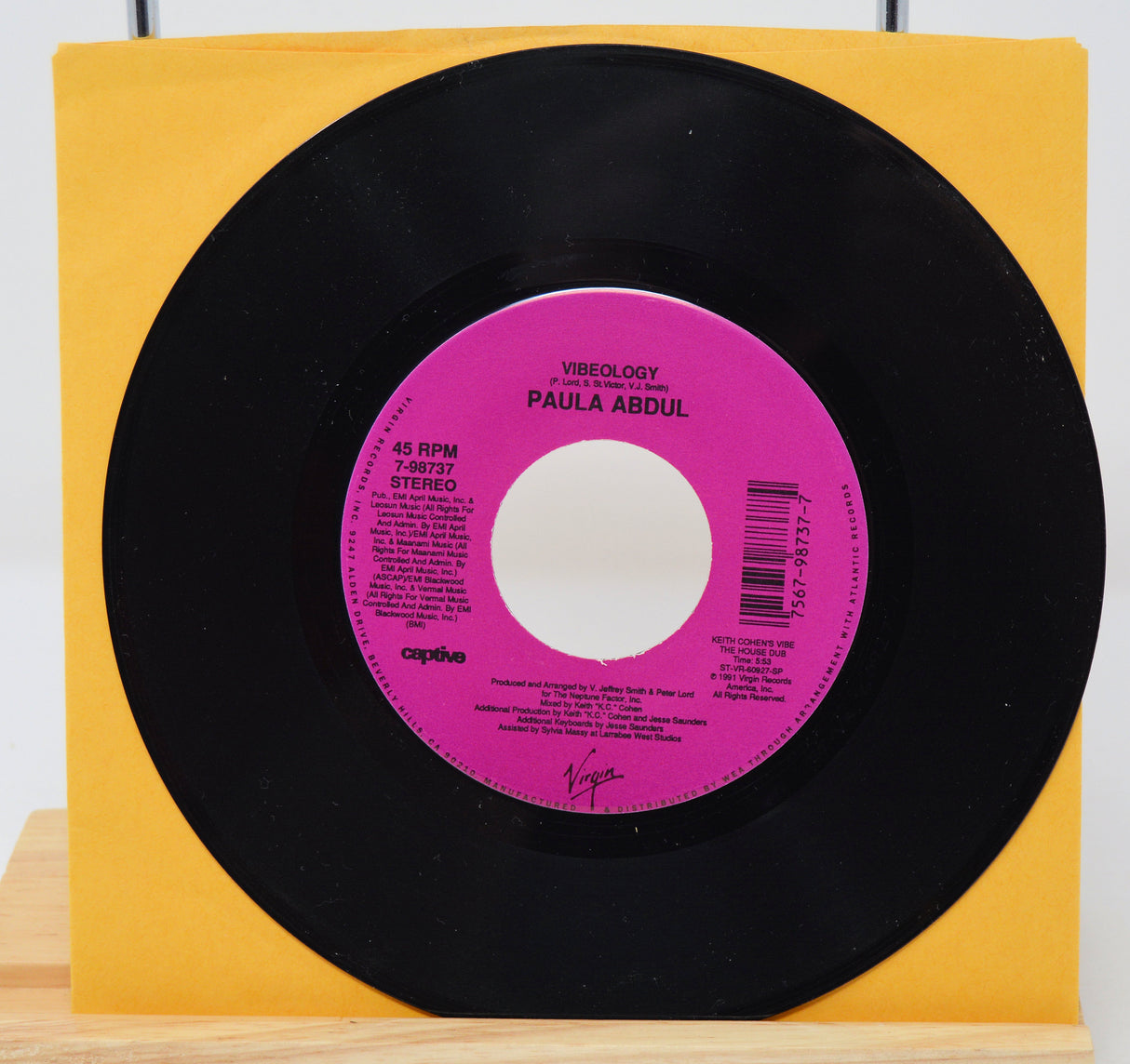 A vinyl record of Paula Abdul's album 'Vibeology' with a pink label on a yellow background.