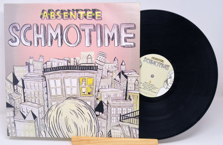 A used vinyl record of Absentee - Schmotime with the album cover in the background.