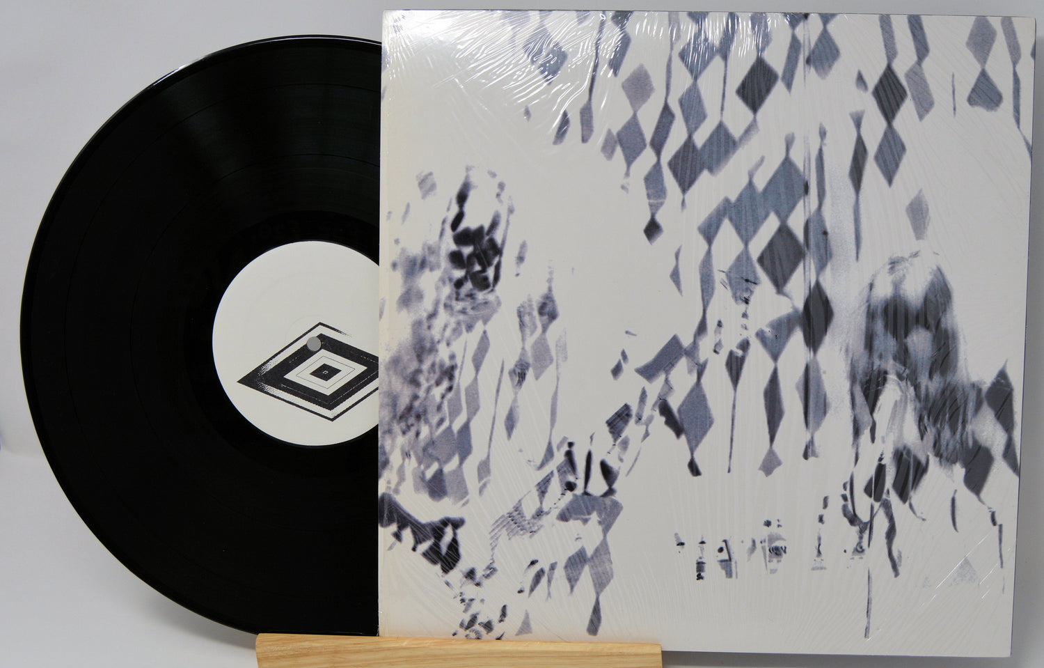 Vinyl record with geometric label and album cover featuring blurred, abstract art