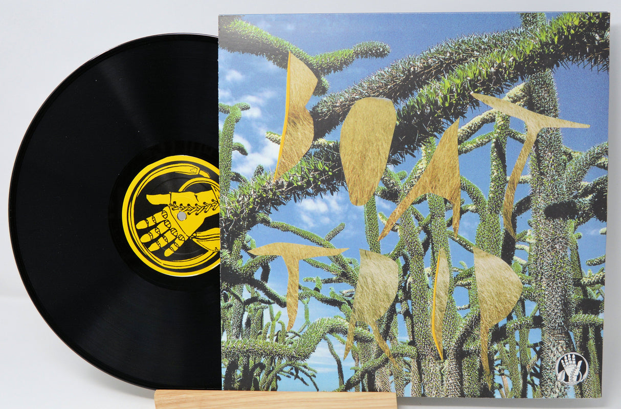 Vinyl record with surreal, abstract cover art featuring spiky green plants and gold shapes under a blue sky