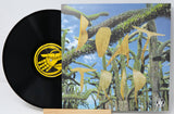 Vinyl record with surreal, abstract cover art featuring spiky green plants and gold shapes under a blue sky