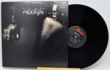Accept's 'Blind Gaze' vinyl record LP with its black cover art sleeve and a black vinyl record partially pulled out, displayed on a small wooden stand against a light gray background.