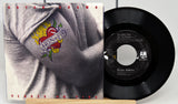 Vinyl record with cover featuring a person wearing a shirt with a heart design, on a white background.
