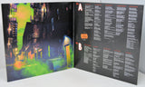 Vinyl record cover with colorful cityscape on one side and tracklist on the other, on a white background.