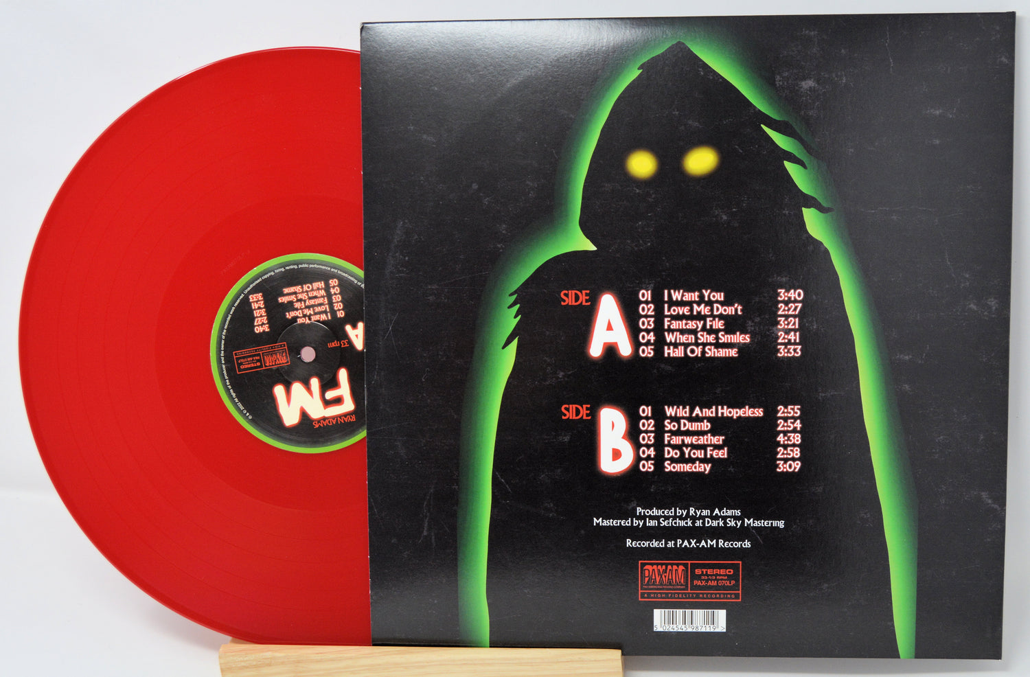 Red vinyl record with a black cover featuring a silhouette and text.