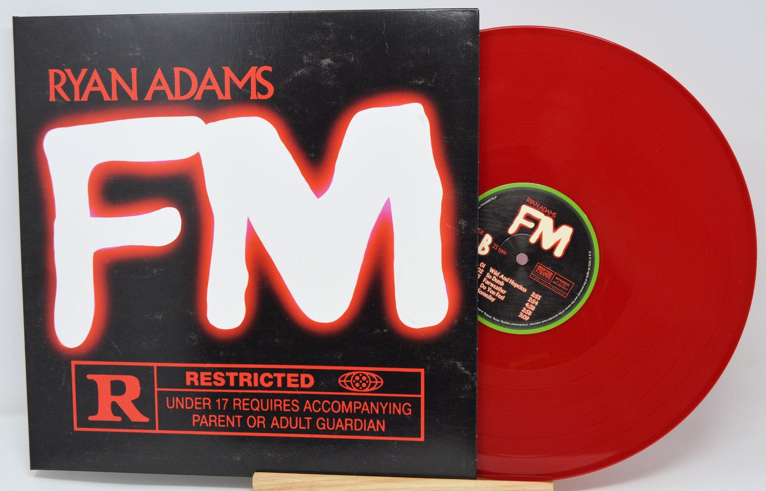 Red vinyl record with 'FM' and 'Ryan Adams' on a black cover