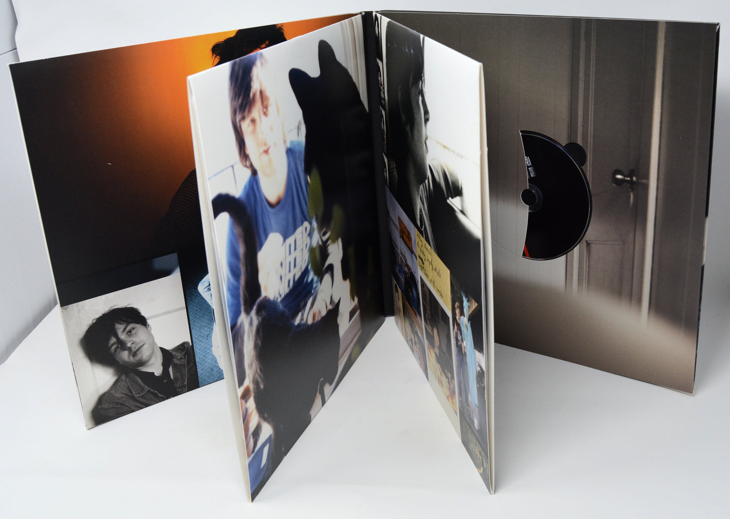 Open DVD case with photos and a CD inside on a white surface