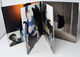 Open DVD case with photos and a CD inside on a white surface