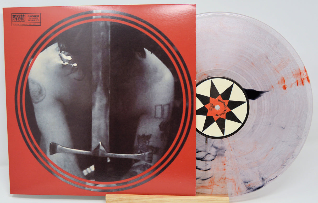 Vinyl record with a red cover featuring a black and white image of a person holding an axe, on a white background.