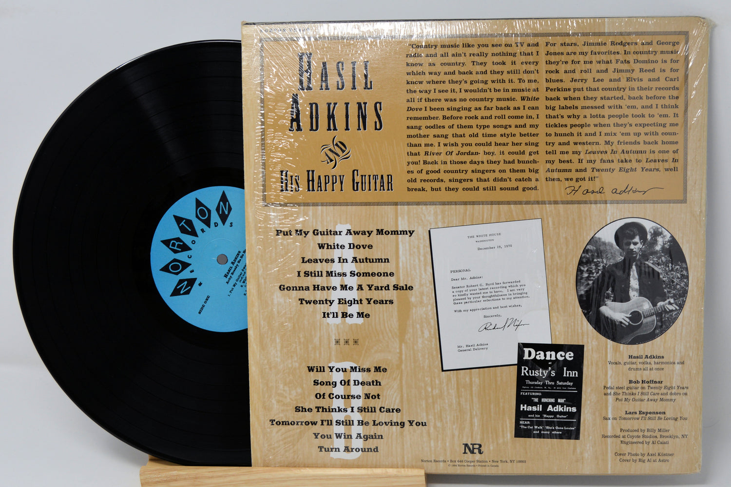 A vinyl record album of 'Achy Breaky Ha Ha Ha' by Hasil Adkins, with a picture of Hasil Adkins on the cover, placed on a record sleeve.