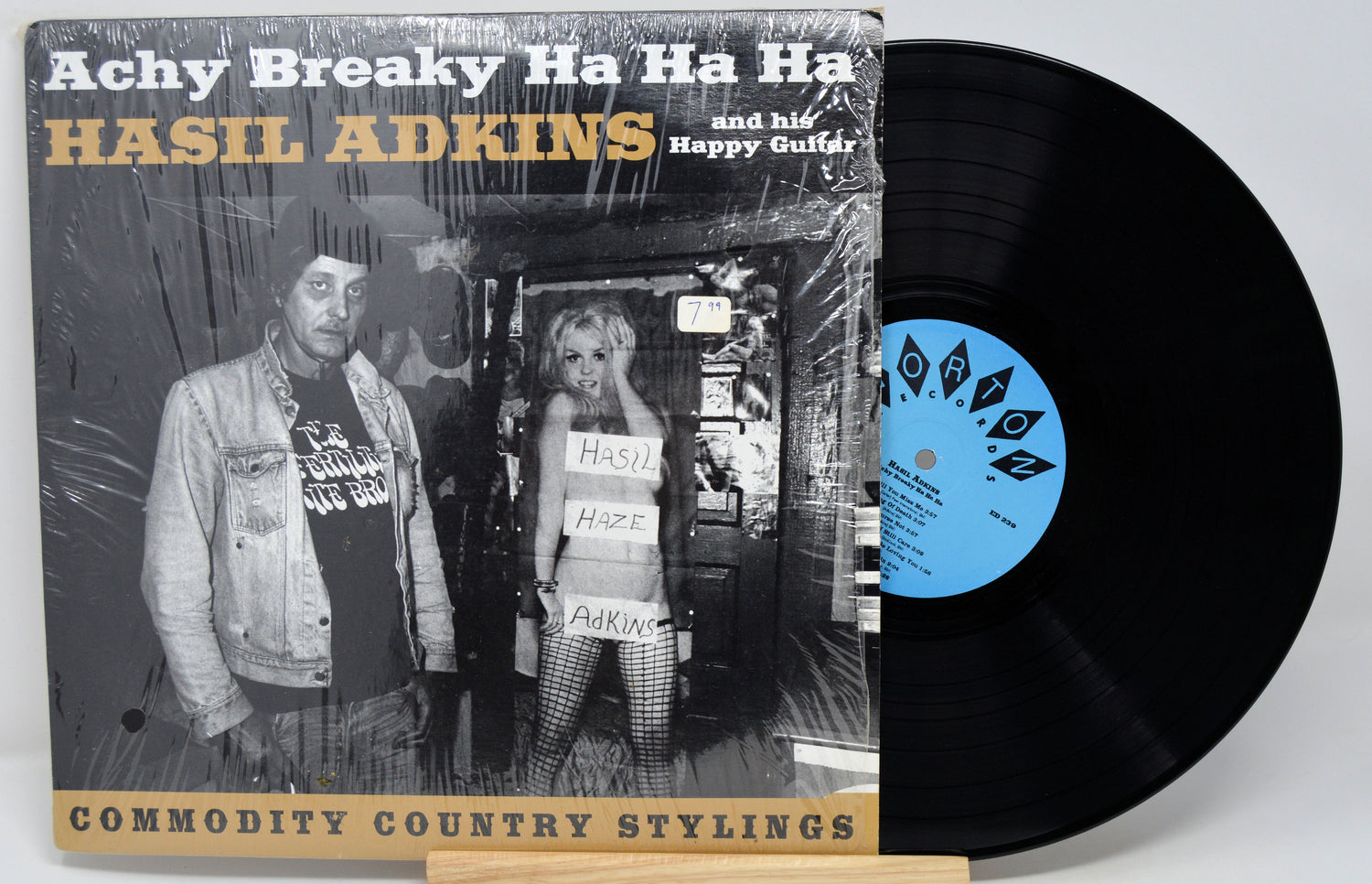 A vinyl record album of 'Achy Breaky Ha Ha Ha' by Hasil Adkins, with a picture of Hasil Adkins on the cover, placed on a record sleeve.