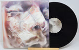 A vinyl record with a purple and black abstract design cover, and a black record disc visible underneath.