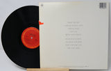 Vinyl record with a red label and its cover displaying text.
