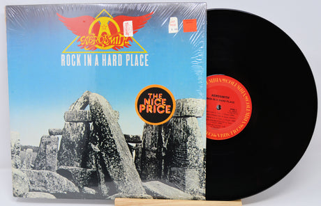 Vinyl record with 'Aerosmith' album cover showing rock formation and red logo.